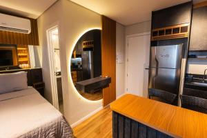 a room with a bed and a kitchen with a refrigerator at Flat Exclusivo Studio Cuiabá 1604 in Cuiabá
