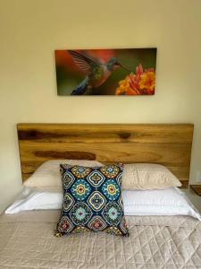 a bed with a wooden headboard and a picture on the wall at Casa Rio Tortuga - Colibri in Tortugal