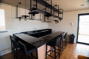 a kitchen with a black counter and black chairs at Flat Exclusivo Studio Cuiabá 1604 in Cuiabá
