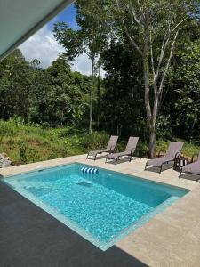 a swimming pool with two chairs and a table at Casa Rio Tortuga - Butterfly in Ojochal +6 photos