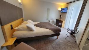 a bedroom with a bed with white sheets and pillows at Le Castelet Sancy - Jardin & Spa in Le Mont-Dore