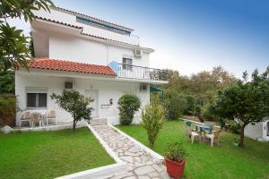 a white house with a yard with a table and chairs at Villa ALEXIS in Koukounaries