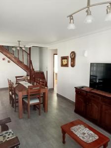 a living room with a dining table and a television at Chalet con pileta in Miramar