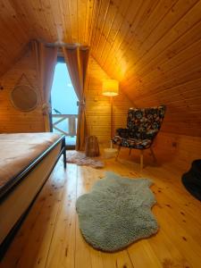 a bedroom with a bed and a chair and a rug at DOMKI KOLOROWE in Marciszów