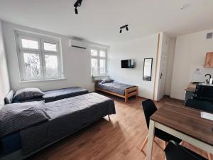 a bedroom with two beds and a table and a desk at Apartamenty przy Galerii in Kluczbork
