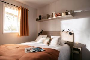 a bedroom with a bed with a book on it at Camping le Dolmen, Carnac, Morbihan in Carnac