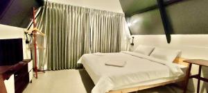 a bedroom with a white bed and a window at บ้านไม้หอมชาเล่ต์ in Suan Phung