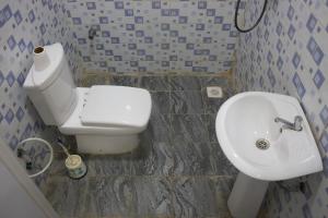 a bathroom with a white toilet and a sink at Oasis Guesthouse Juba in Juba +4 photos