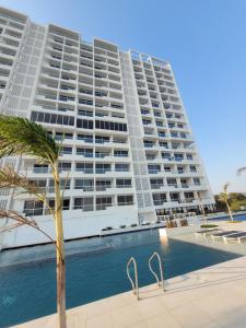 a large apartment building with a swimming pool and a palm tree at Porto Horizonte suite 424 in Playa Bello Horizonte