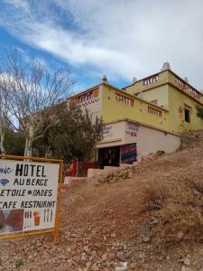 a building on a hill with a sign in front of it at Riad restaurante Étoile dades Camping in Imdiazene +14 photos