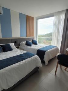 two beds in a room with a large window at Porto Horizonte suite 424 in Playa Bello Horizonte +31 photos