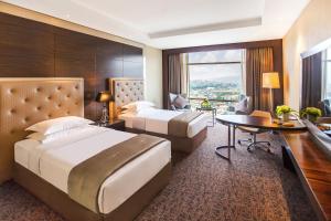 a hotel room with two beds and a desk at The Biltmore Tbilisi Hotel in Tbilisi City