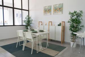 a white dining room with a white table and chairs at Apartamento en primera línea de la playa in Arinaga