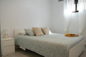 a white bedroom with a bed with a window at Apartamento en primera línea de la playa in Arinaga