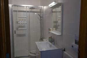 a white bathroom with a shower and a sink at Apartamento en primera línea de la playa in Arinaga +23 photos