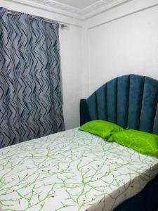 a bed with a green pillow next to a blue chair at Eilena prestige in Douala