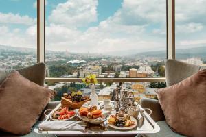 einen Tisch mit Essen drauf mit Blick auf die Stadt in der Unterkunft The Biltmore Tbilisi Hotel in Tbilisi City