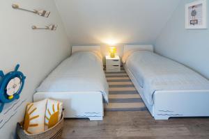 two twin beds in a small room with a lamp at Küstenkoje in Neßmersiel