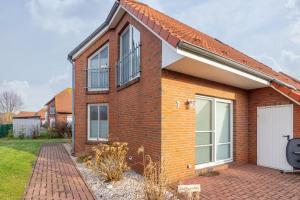 a brick house with a white door and windows at Küstenkoje in Neßmersiel
