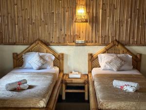 a room with two beds and a table and a lamp at Bambuu in Gili Islands