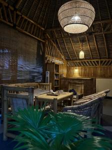 a restaurant with wooden tables and chairs and a chandelier at Bambuu in Gili Islands