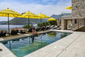 a woman sitting in a swimming pool with umbrellas at Santa Boka Small Luxury Hotels of the World in Perast