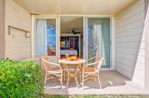 a table and chairs on a patio with a window at Islander on the Beach 131 in Kapaa