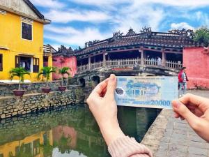 a person holding up a picture of a building at VNJ Capsule 388 in Hoi An