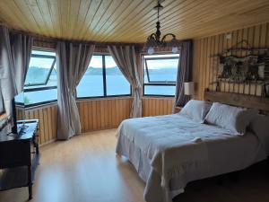 a bedroom with a large bed with windows at Casa de la bahia de Chiloé in Castro