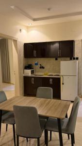 a kitchen with a table and chairs and a refrigerator at وادي برزان للشقق المخدومة in Hail
