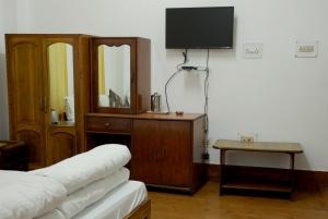 a room with a tv and a dresser and a bed at OS Hotel Pomra in Gangtok