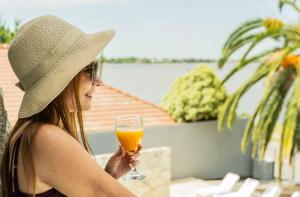 a woman wearing a hat holding a glass of orange juice at Palmas de la Laguna by Posada Suiza in San Miguel del Monte