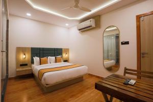 a bedroom with a bed and a mirror and a table at De Classico Hotel Apartment in Mumbai