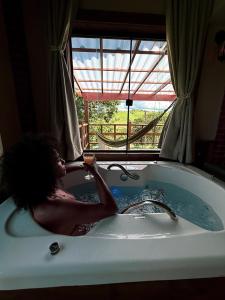 a woman sitting in a bath tub with a drink in it at Pousada Sons do Silêncio in Socorro