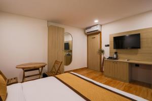 a hotel room with a bed and a flat screen tv at De Classico Hotel Apartment in Mumbai
