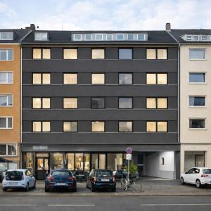 a black building with cars parked in a parking lot at Apartments KR in Cologne