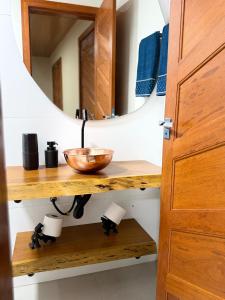 a bathroom with a mirror and a bowl on a wooden shelf at Recanto Tavares in Linhares +55 photos
