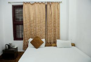 a bedroom with a white bed and a window at OS Hotel Pomra in Gangtok