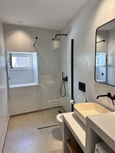 a bathroom with a shower and a sink and a mirror at Little Kamara Ios in Ios Chora