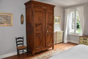 a bedroom with a large wooden cabinet next to a bed at Residence le Petit Paradis in Labastide-Rouairoux