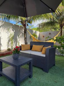 a blue wicker couch and a table under an umbrella at Recanto Tavares in Linhares