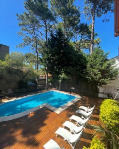 a swimming pool with chaise lounge chairs next to a wooden deck at Sintra Aparts in Mar de las Pampas