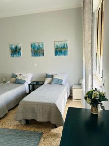 a bedroom with two beds and a table and paintings at Casa Acqua e Sale - 50 mt dal mare in Fano