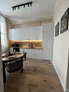 a kitchen with white cabinets and a table and chairs at Old Town Rynek Apartament in Grudziądz +2 photos