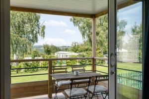 a screened porch with a table and chairs and a view at Camping Papillon Bouillon - Vakantiehuis Premium Rustige Locatie in Bouillon