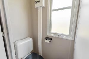 a bathroom with a toilet and a window at Camping Papillon Bouillon - Vakantiehuis Premium Rustige Locatie in Bouillon +18 photos