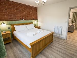 a large bed in a room with a brick wall at Foxwhelp in Ledbury +3 photos