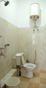a bathroom with a toilet and a light on the wall at OS Hotel Pomra in Gangtok +28 photos