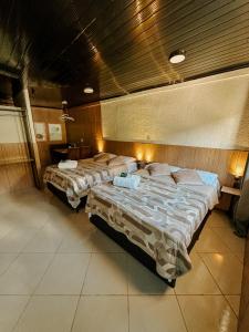 two beds in a large room with wooden walls at Espaços Cardoso, HORIZONTE- amplitude e respiro in Igrejinha