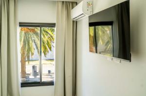 a room with two windows and a palm tree at Palmas de la Laguna by Posada Suiza in San Miguel del Monte